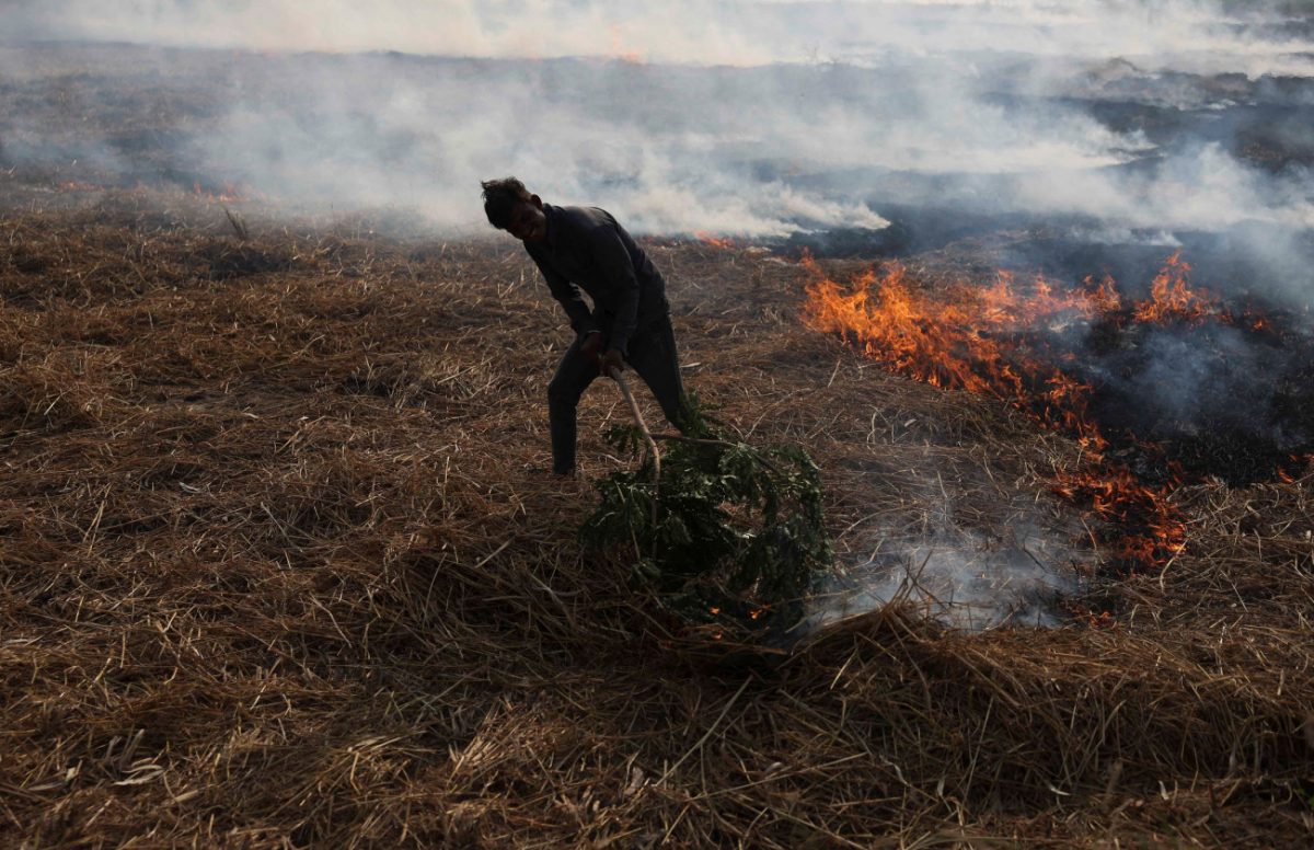 Αγρότης καίει ξερά χόρτα στο Αχμενταμπάντ της Ινδίας. Είναι η σημαντικότερη πηγή ρύπανσης τον χειμώνα (Reuters)